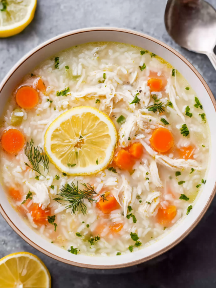 A bowl of soup with lemon and rice.