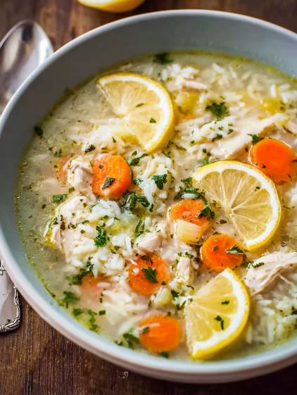 A bowl of soup with lemon slices and rice.