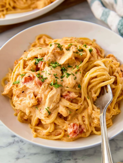 A white plate with a fork and spaghetti with chicken.