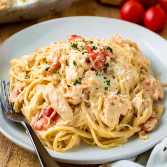 A plate of spaghetti with chicken and tomatoes.