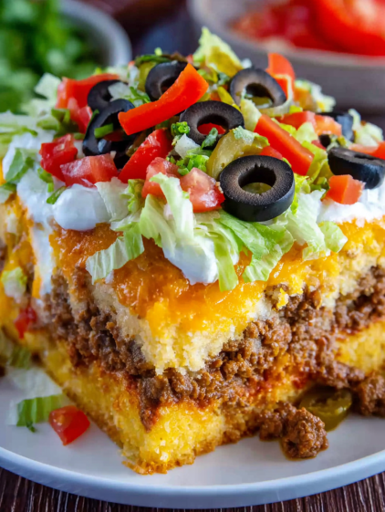 A delicious cornbread taco bake with black olives and tomatoes.
