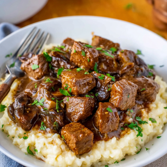 A plate of beef stew with a fork on the side.