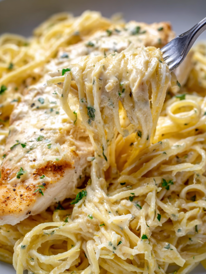 A fork is in a bowl of pasta with chicken.