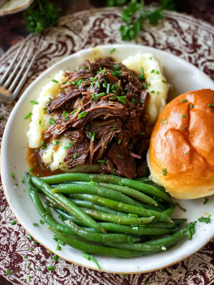 A plate of food with a green bean, a piece of meat, and a roll.