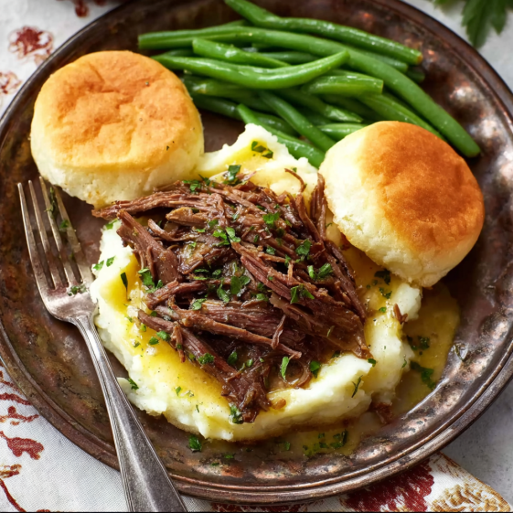 A plate of Mississippi pot roast with green beans and biscuits.