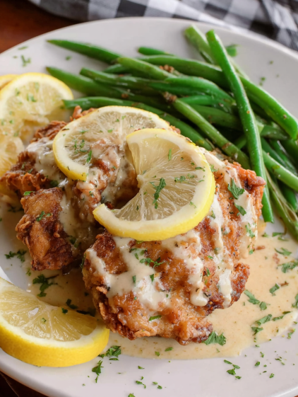 A plate of chicken with lemon and garlic sauce.