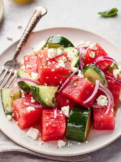 A plate of watermelon salad with feta cheese and onions.