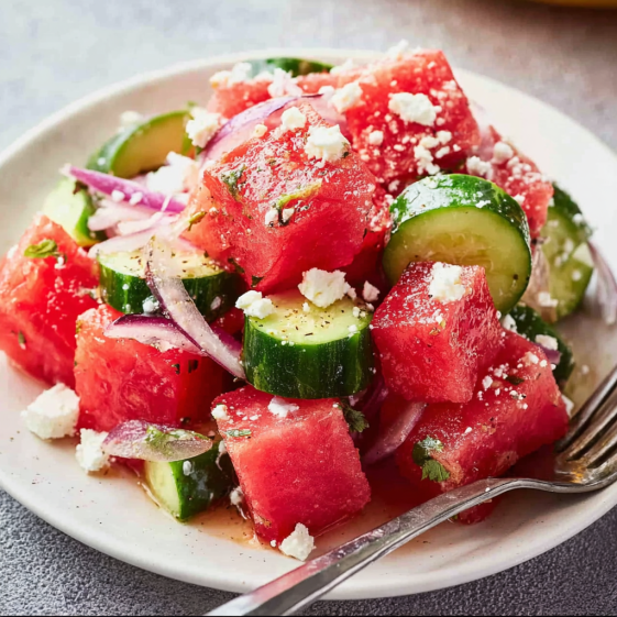A plate of watermelon salad with feta cheese and onions.
