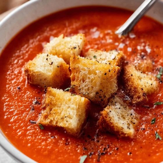 A bowl of tomato soup with garlic croutons.