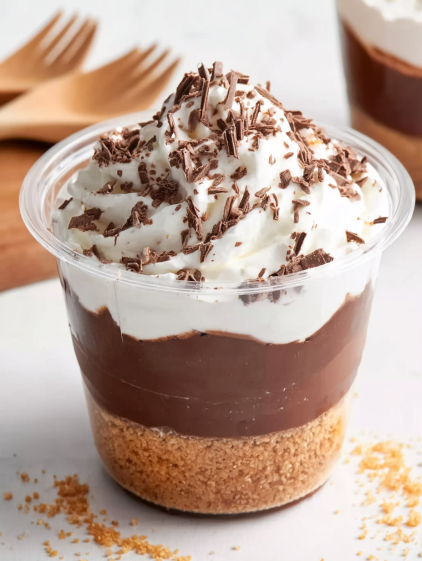 A cup of chocolate parfait with whipped cream.