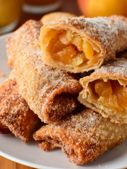 Peach cobbler egg rolls on a plate.