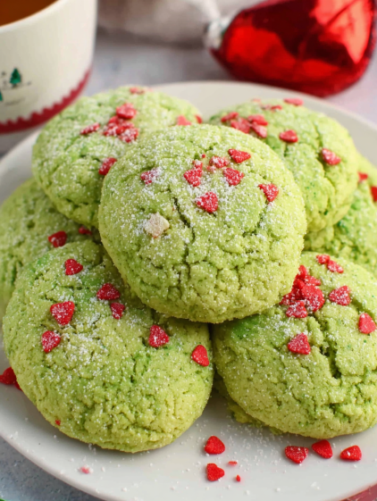 A plate of green cookies with red hearts on top.