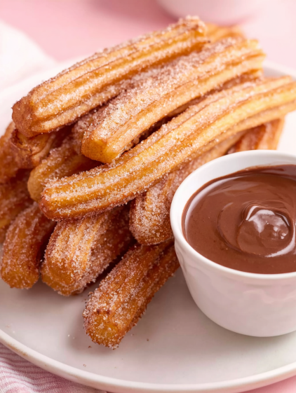 A plate of churros with a bowl of chocolate sauce.