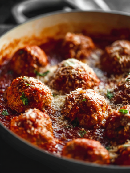 A pan of baked meatballs with sauce.