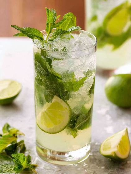 A glass of mojito with mint leaves and lime slices.