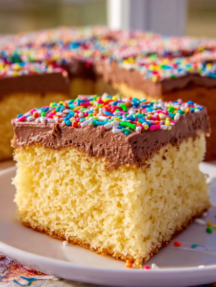 A slice of yellow cake with chocolate frosting.