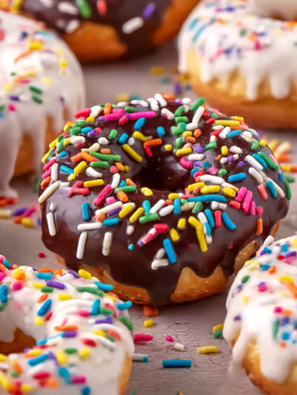 A plate of donuts with sprinkles and chocolate frosting.