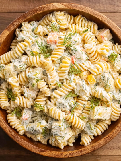 A bowl of pasta salad with dill pickles.