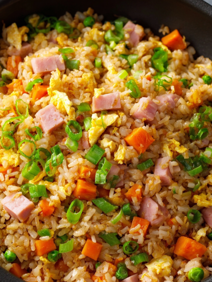 A close up of a plate of ham fried rice.