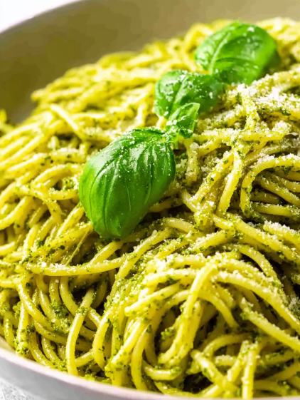 A bowl of pasta with pesto sauce.