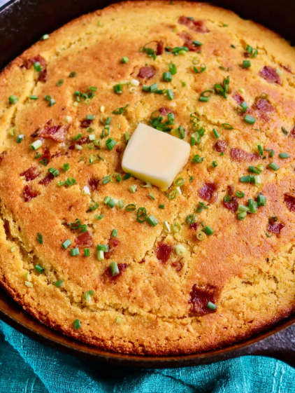 A slice of bacon cornbread with a butter pat on top.
