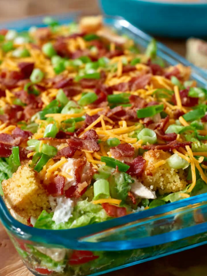 A dish of cornbread salad with bacon and cheese.
