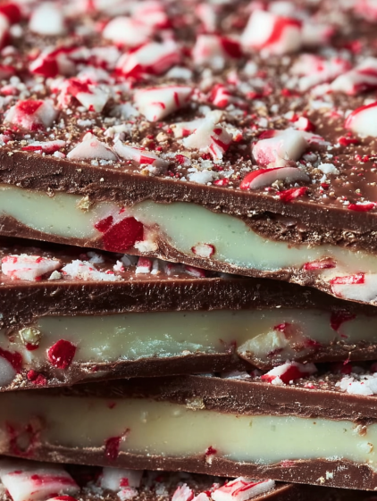 A chocolate cake with white icing and red and green sprinkles.