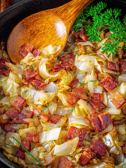 A close up of a dish with fried cabbage, onions and bacon.