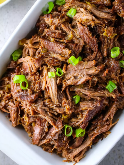 A white bowl filled with meat and green onions.