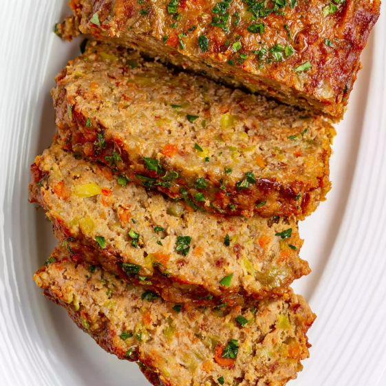 A plate of meatloaf with carrots on top.