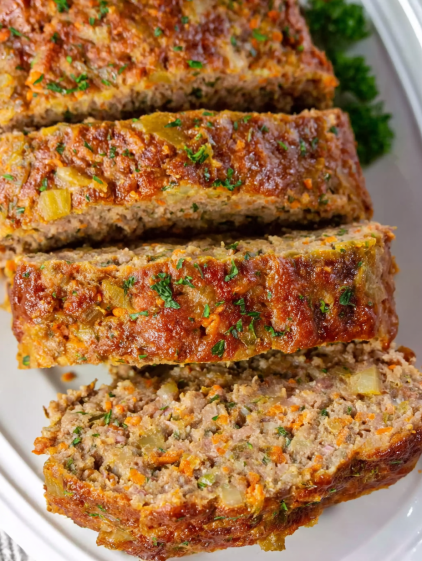 A slice of meat with carrots on top.