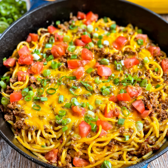 A bowl of spaghetti with meat and tomatoes.