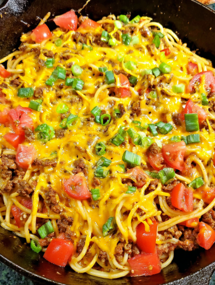 A bowl of spaghetti with meat sauce and vegetables.