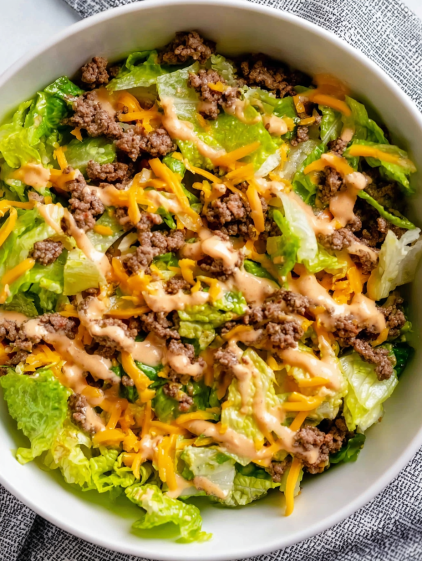 A bowl of salad with cheese and dressing.