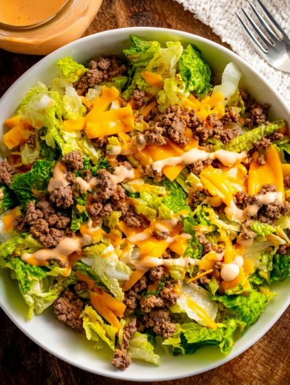 A bowl of salad with meat and cheese.