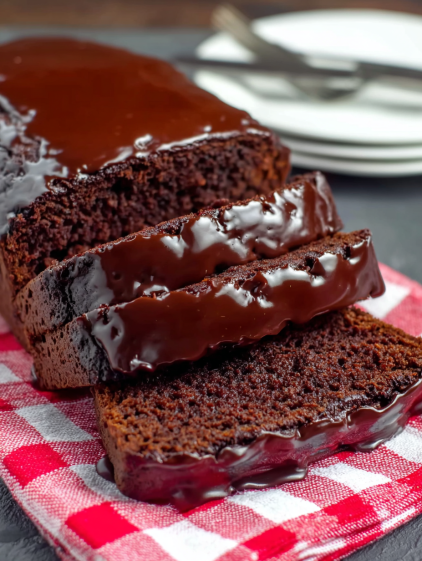 A slice of chocolate cake on a red and white checkered cloth.