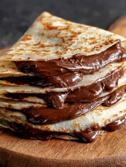 A stack of tortillas with chocolate sauce on top.