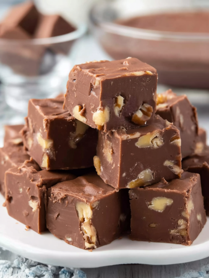 A stack of chocolate squares with nuts on top.