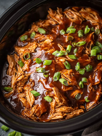 A close up of a slow cooker with barbecue chicken in it.