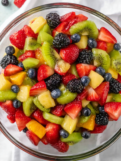 A bowl of fruit with strawberries, blueberries, kiwi, and blackberries.
