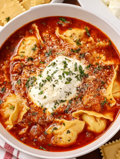 A bowl of pasta with a white sauce on top.