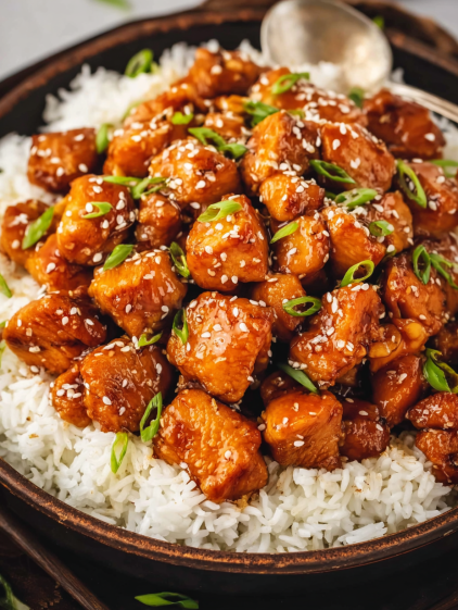 A bowl of rice with chicken and vegetables.