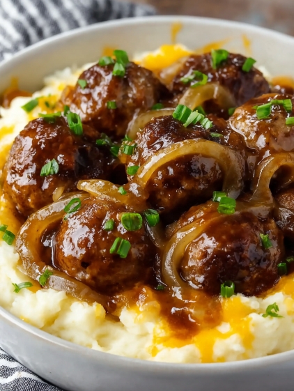 A bowl of food with meatballs and onions.
