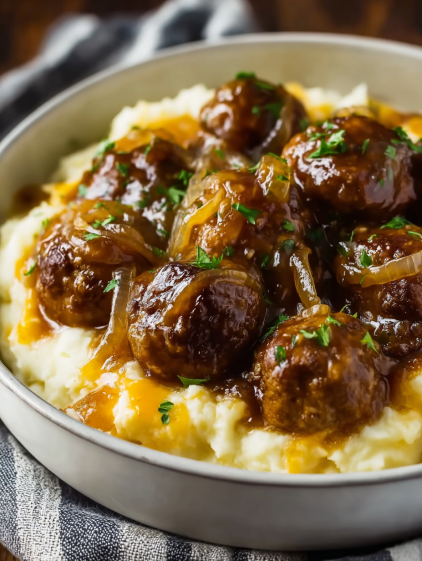 A bowl of food with meatballs and onions.