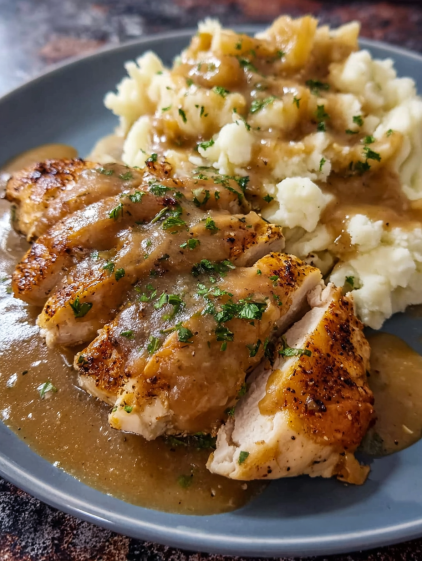 A plate of chicken and potatoes with gravy.