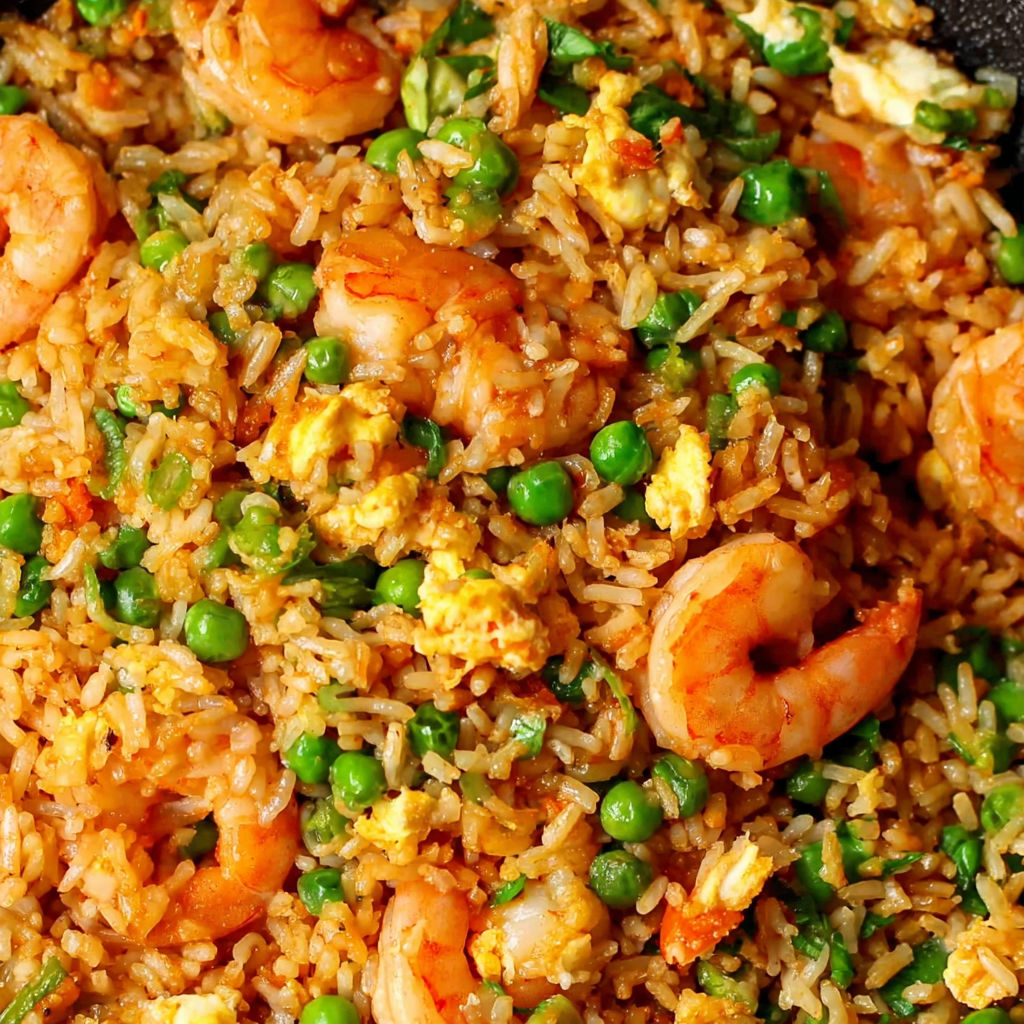 A plate of shrimp fried rice with peas and egg.