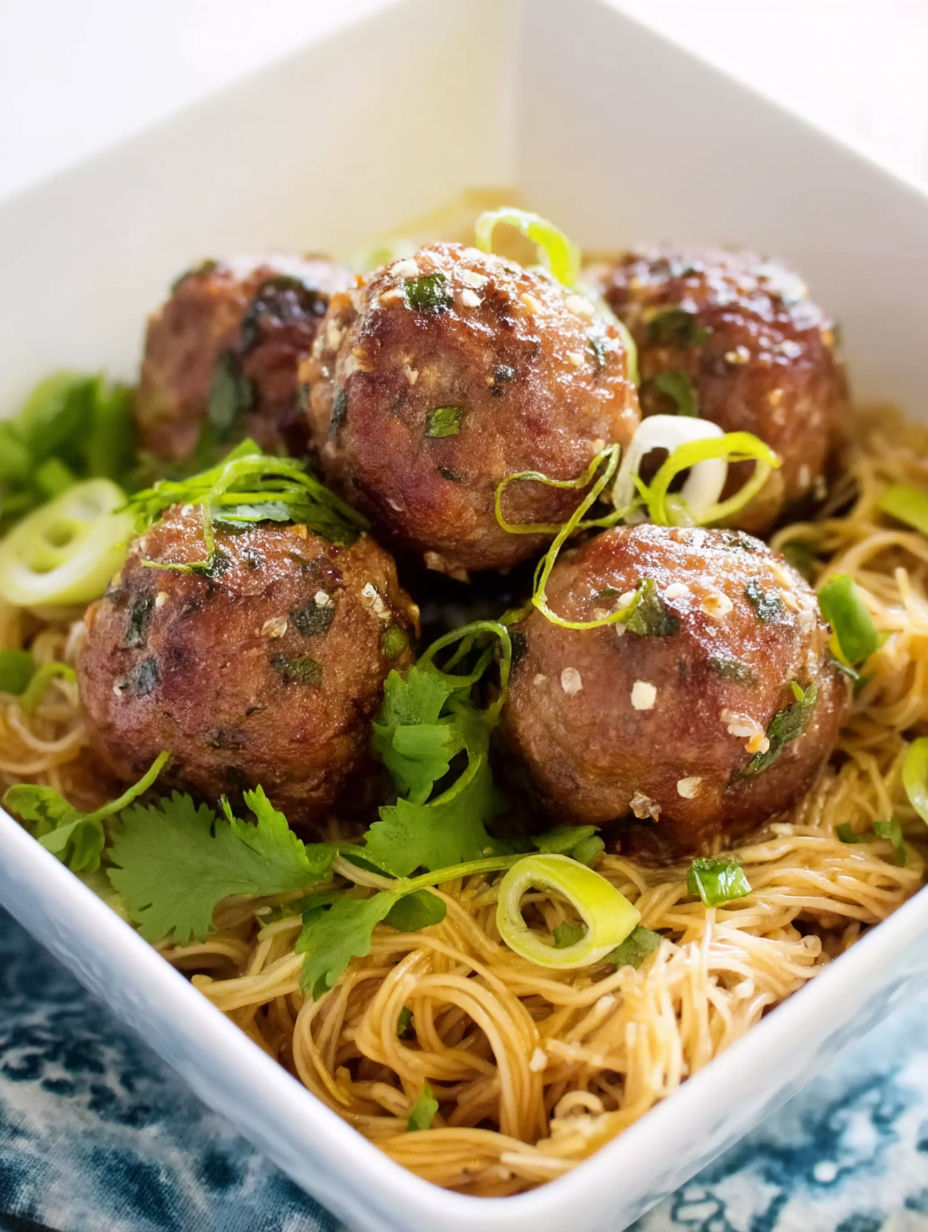 A bowl of Asian meatballs with noodles.