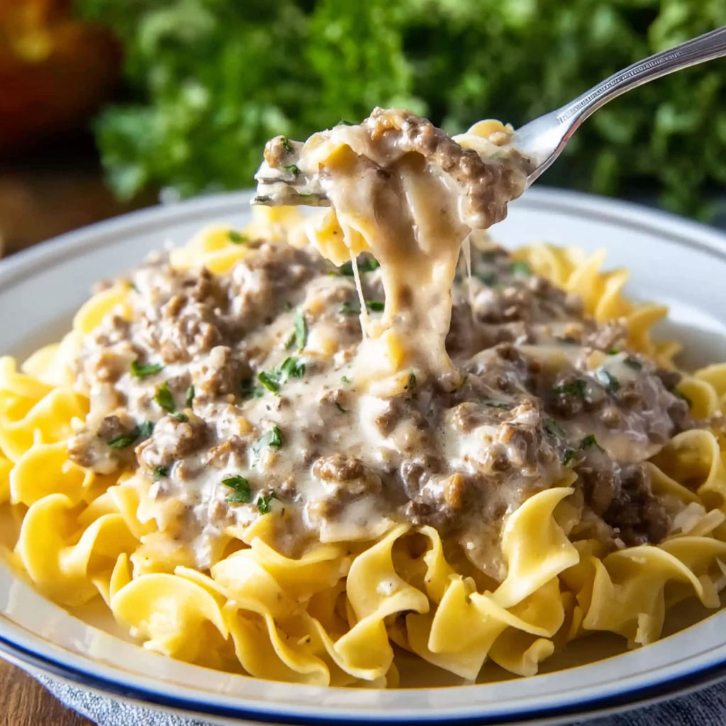 A plate of ground beef stroganoff with a fork in it.