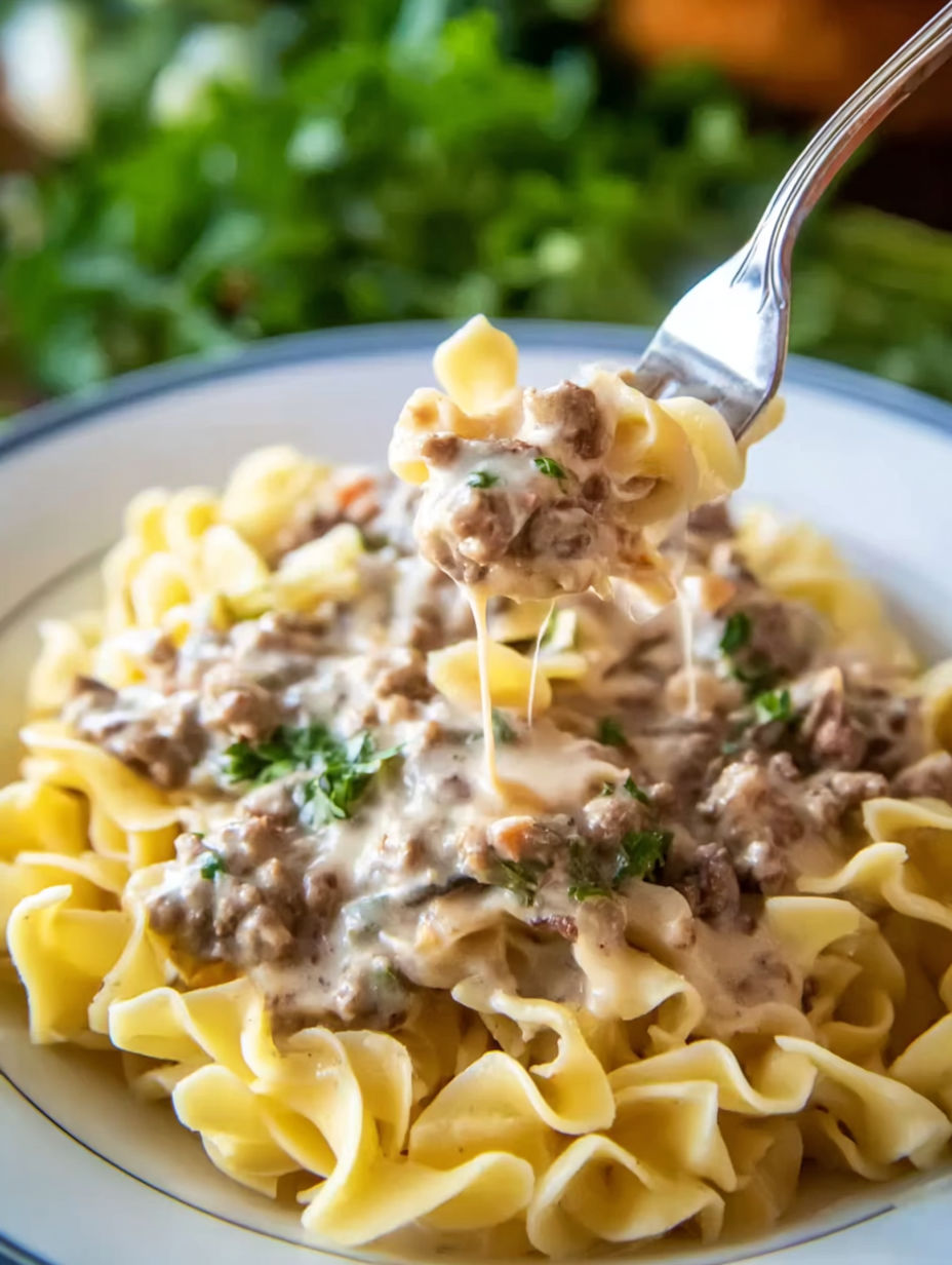 A fork is being used to eat a bowl of ground beef stroganoff.