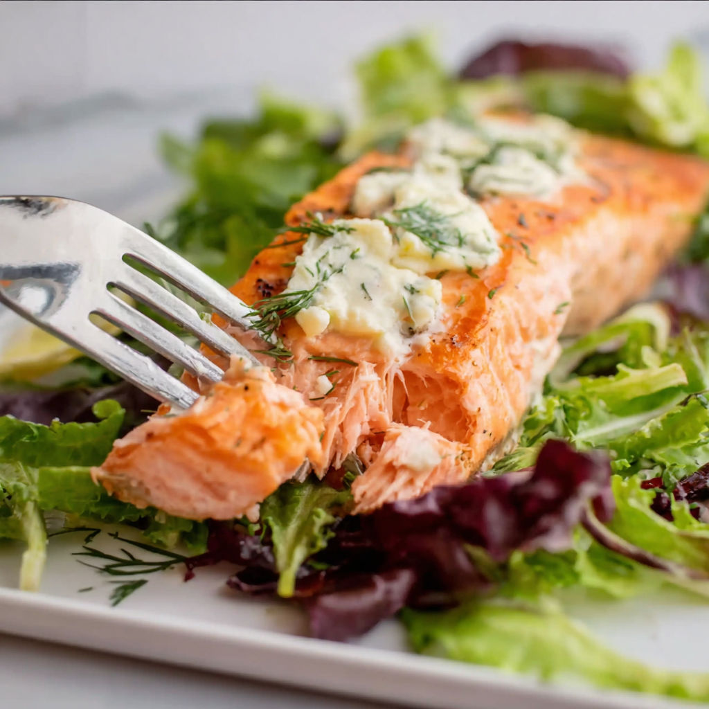 A fork is stuck in a piece of salmon.